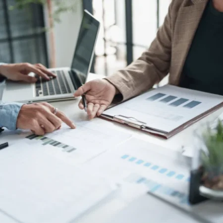 Teamarbeit an Laptop und Dokumenten mit Fokus auf Virtualisierung und Marketing-Strategien